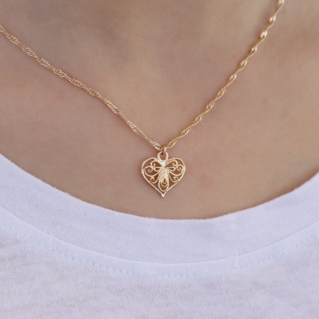 עשוי לכלול: שרשרת לב זהב פיליגרן עם תליון דבורה קטן במרכז. השרשרת היא בסגנון חבל עדין. תליון הלב כולל עיטורים מורכבים. שרשרת זהב זו היא תכשיט עדין ואלגנטי.