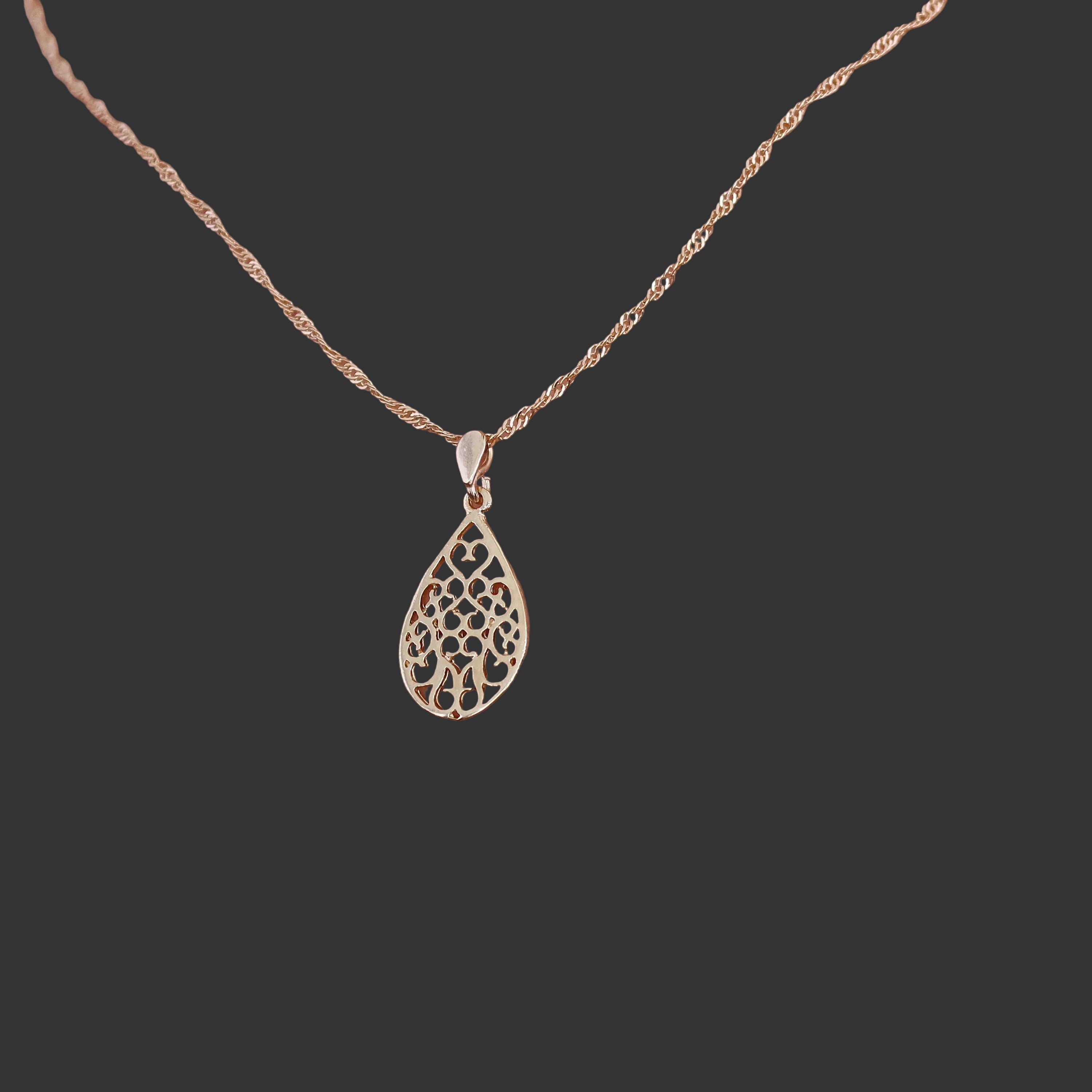 עשוי לכלול: שרשרת תליון דמעה בצבע זהב. השרשרת כוללת שרשרת עדינה מזהב ורוד ותליון עם עיצוב חיתוך. התליון מעוצב כדמעה וכולל פרטים פרחוניים מורכבים. השרשרת מוצגת על דוגמנית, ומדגישה את גודל התליון ופרטי הפרטים שלו. השרשרת היא בסגנון חבל עדין. הסגנון הכללי אלגנטי ונשי.