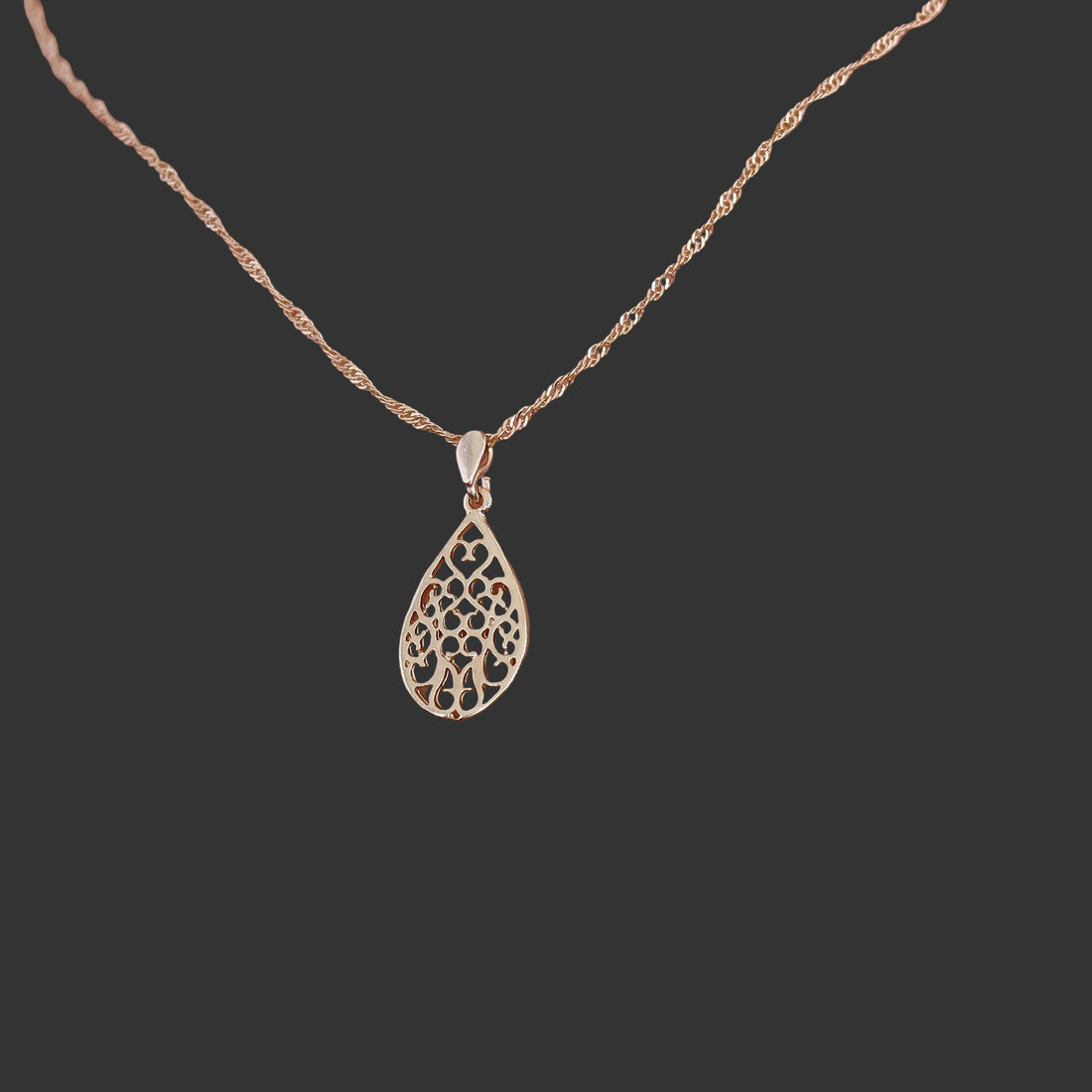 עשוי לכלול: שרשרת תליון דמעה בצבע זהב. השרשרת כוללת שרשרת עדינה מזהב ורוד ותליון עם עיצוב חיתוך. התליון מעוצב כדמעה וכולל פרטים פרחוניים מורכבים. השרשרת מוצגת על דוגמנית, ומדגישה את גודל התליון ופרטי הפרטים שלו. השרשרת היא בסגנון חבל עדין. הסגנון הכללי אלגנטי ונשי.