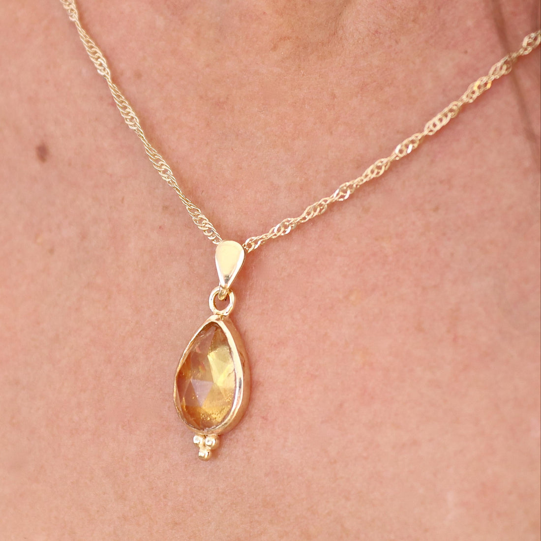עשוי לכלול: שרשרת זהב עם תליון בצורת דמעה ועליו אבן חן צהובה שקופה