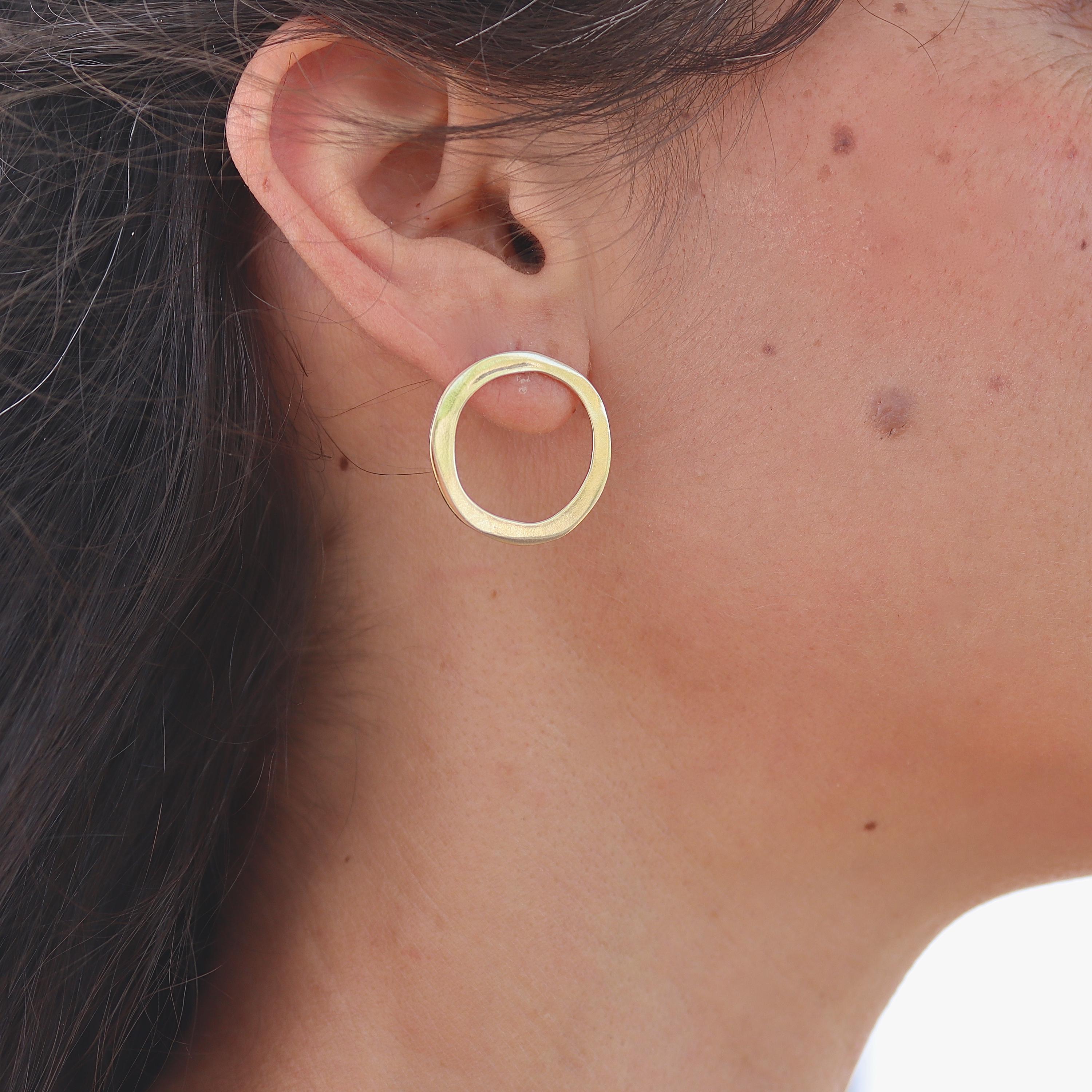 עשוי לכלול: זוג עגילי חישוק זהב. העגילים פשוטים ובעלי צורה עגולה.