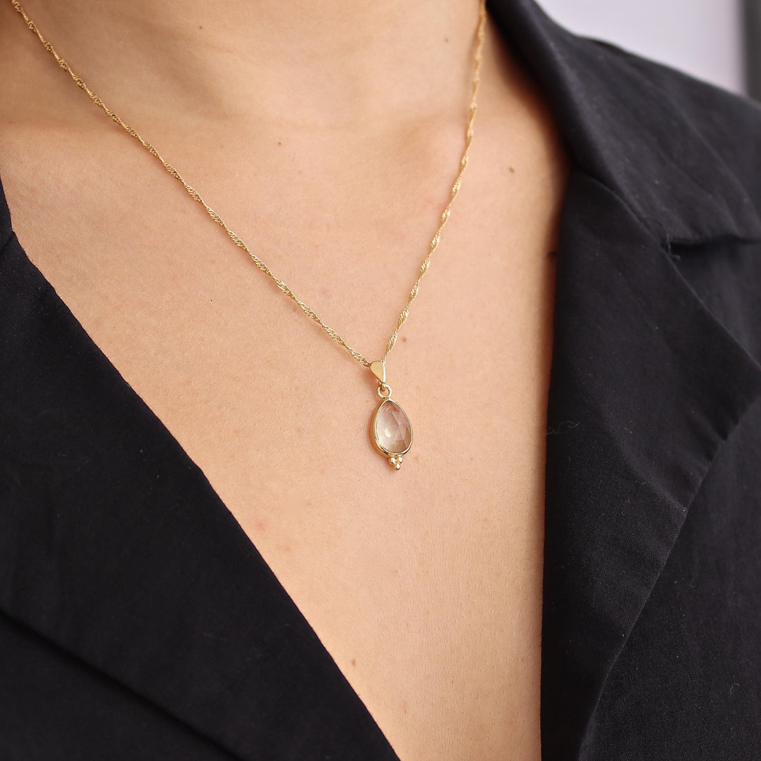 עשוי לכלול: שרשרת זהב עם תליון בצורת דמעה ועליו אבן חן חומה בהירה שקופה