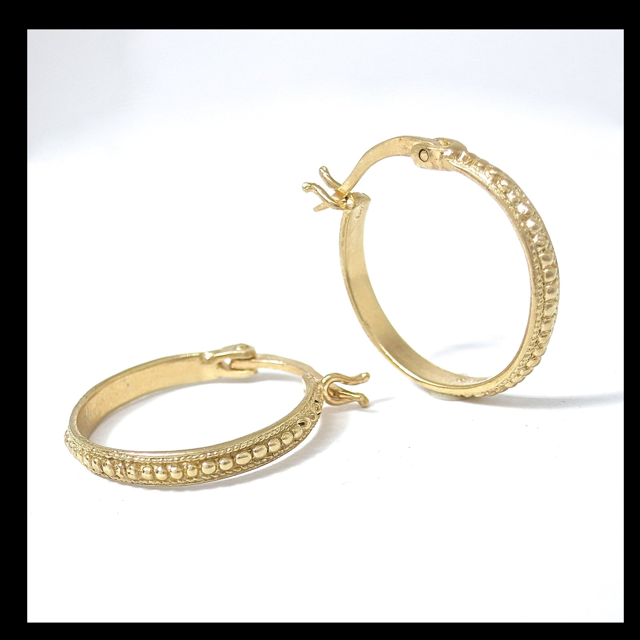 עשוי לכלול: שני עגילי חישוק זהב עם עיצוב חרוזים מסביב לקצה.