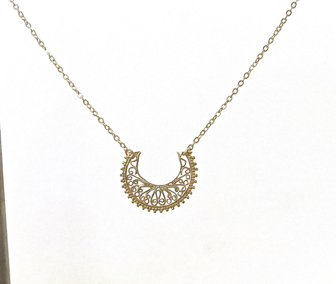 עשוי לכלול: שרשרת סהר זהב עשויה פיליגרן. התליון כולל פרטים מורכבים ועדינים ותלוי על שרשרת זהב משובחת. צורת הסהר מעוטרת בדוגמא פרחונית חוזרת. שרשרת אלגנטית זו מושלמת להוספת נגיעה של קסם בוהמייני לכל תלבושת.