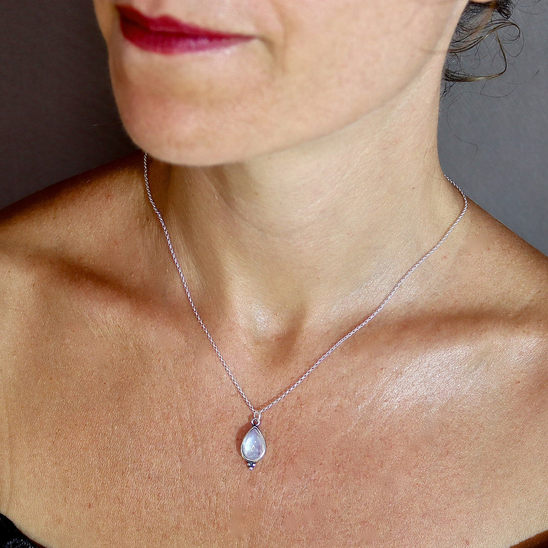 עשוי לכלול: שרשרת כסף עם תליון אבן ירח בצורת דמעה.