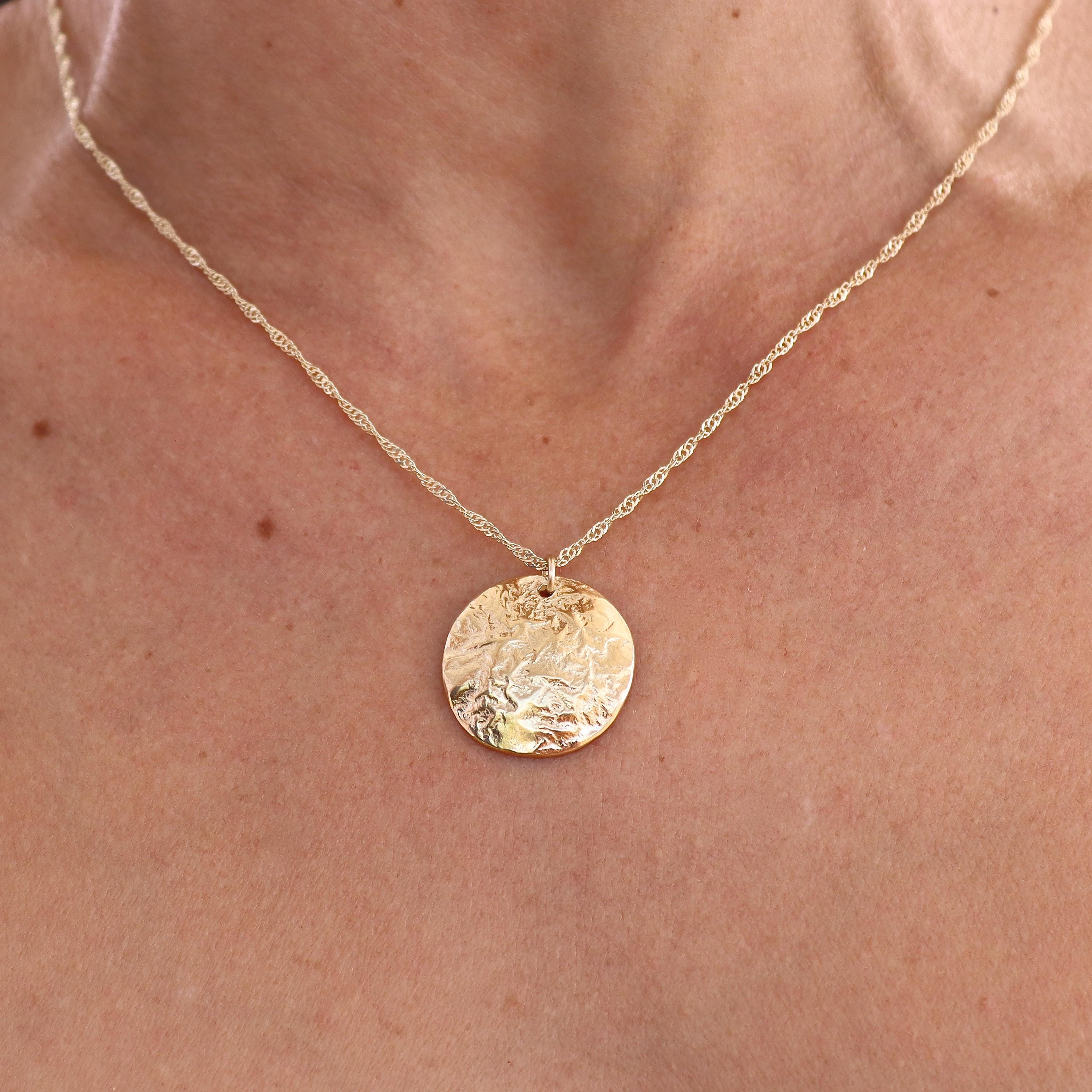עשוי לכלול: שרשרת זהב עם תליון זהב עגול, בעל טקסטורה.