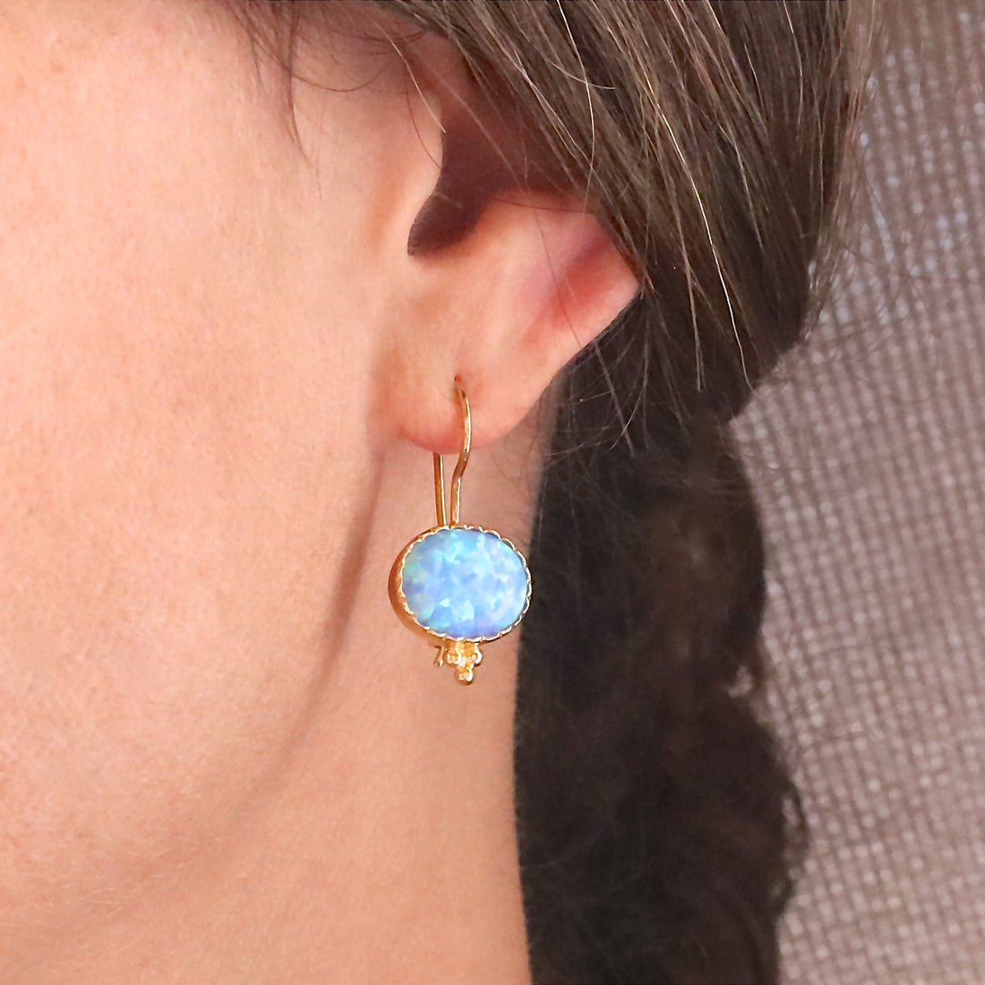 עשוי לכלול: עגילי זהב אובליים עם אבן אופל תכלת