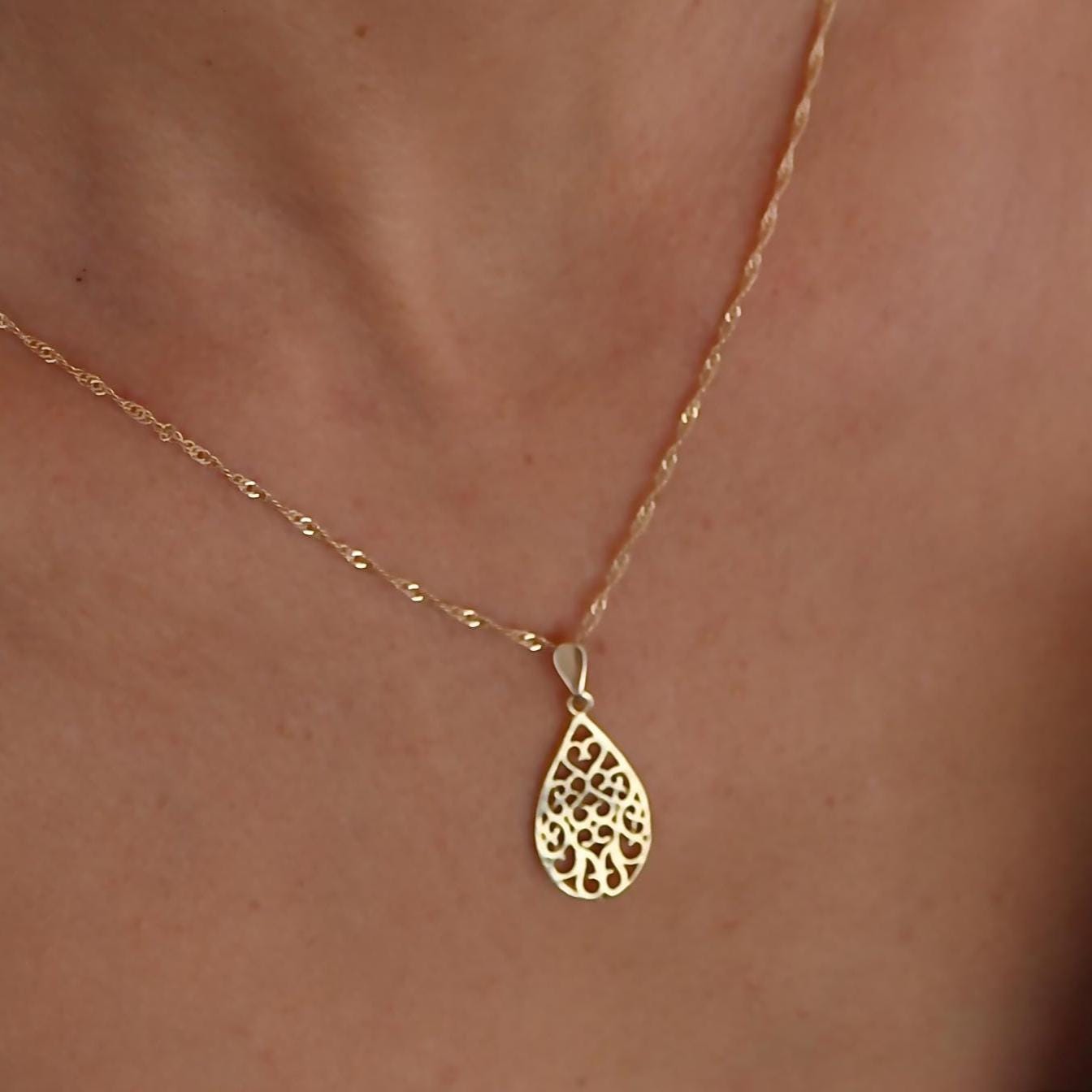 עשוי לכלול: שרשרת זהב עם תליון עדין ומורכב בצורת דמעה. התליון עשוי זהב ובעל עיצוב פיליגרן.