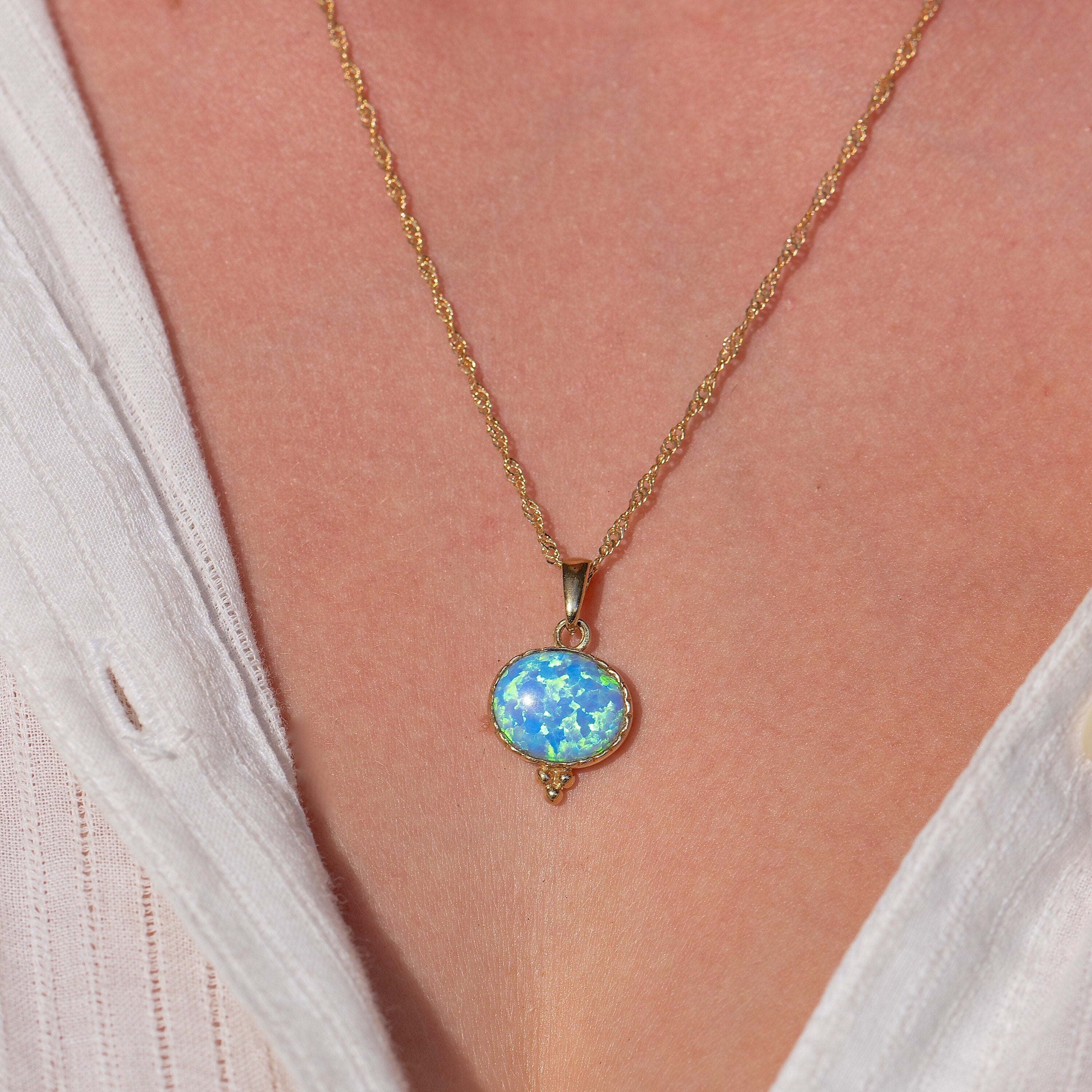 עשוי לכלול: שרשרת זהב עם תליון אופל תכלת. התליון בצורת אליפסה ובעל גבול זהב.