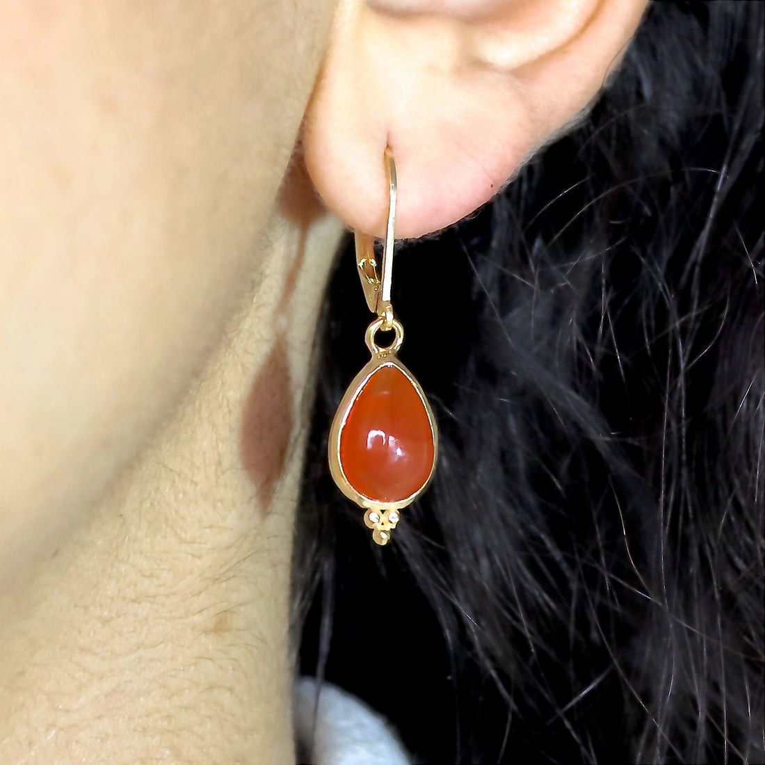 עשוי לכלול: עגילי זהב תלויים בצורת קרנליאן בצורת דמעה. העגילים כוללים אבן חן קרנליאן חלקה ומלוטשת בצורת אגס, משובצת במסגרת זהב. לעגילי הזהב "סוגר חות" יש חרוזים דקורטיביים קטנים מתחת לאבן החן. עגילים אלגנטיים אלה מושלמים להוספת נגיעה של תחכום לכל תלבושת.