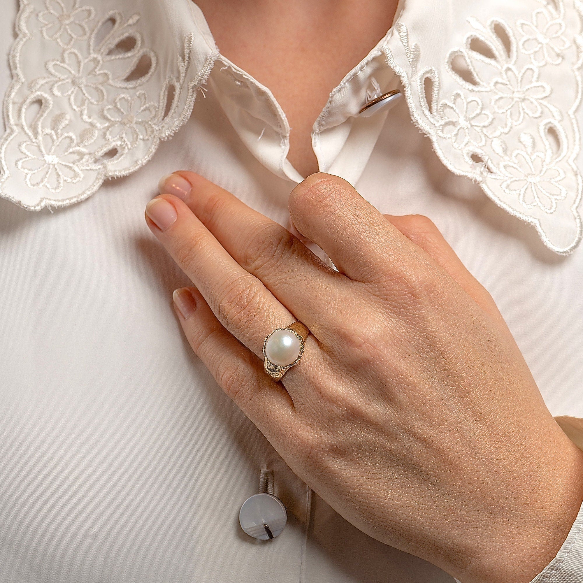 עשוי לכלול: טבעת זהב עם פנינה לבנה גדולה משובצת במסגרת דקורטיבית.